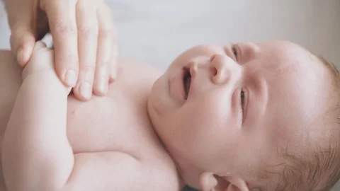 Infant boy with plump cheeks lies on baby changing table Stock-Footage 113463932