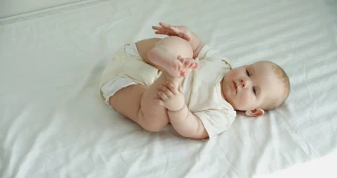 Infant child learning to turn over on blanket. Portrait of baby girl with Stock Footage 250190742