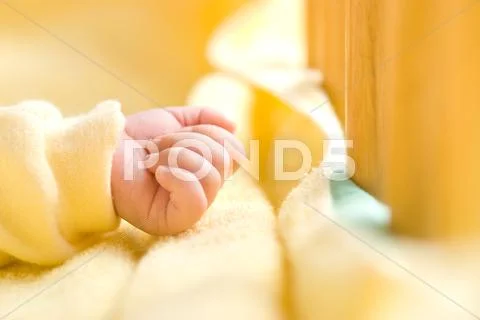 Infant hand in baby bed with wooden fence Stock Photos