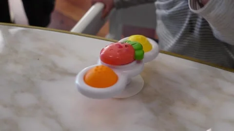 Infant hand touching fruit spinner toy on marble Stock Footage 301367954