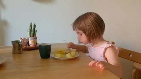 Infant leaning forward to bite pancake during cozy morning family meal Stock Footage 321029100