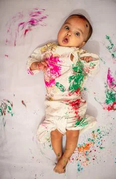 Infant lying at bed and paying holi in traditional dress with multicolor fr.. Stock Photos