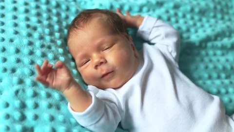 Infant lying on blue blanket and starts to cry Stock Footage 84182846