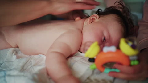 Infant lying on stomach while caregiver gently massages baby back during Video stock 331059273