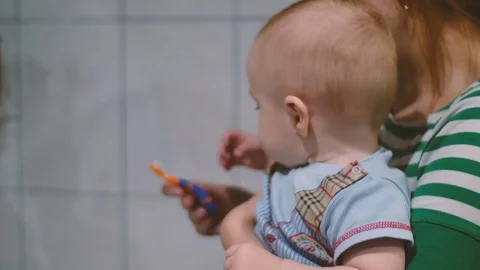 Infant Mom cleans first teeth Video stock 83603837