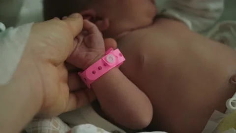 Infant newborn hand arm wrist pink girl band hospital  identification wristband Stock Footage