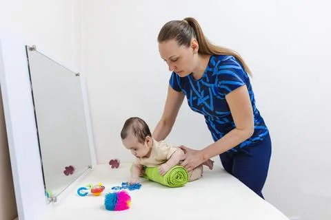 Infant physiotherapy with prone positioning and mirror interaction to suppo.. Stock Photos