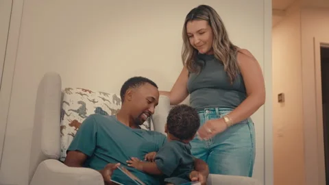 Infant Reading on Black Dad’s Lap with Hispanic Mom in Bedtime Routine Stock Footage 317843661