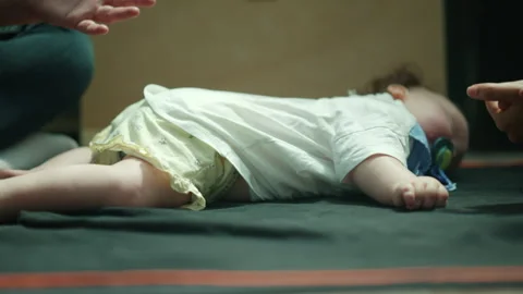 Infant resting peacefully on a dark mat indoors, experiencing deep rest and Stock Footage 339806644
