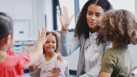 Infant school kids giving their teacher a high five in the classroom after Stock Footage