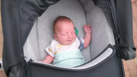 Infant in stroller enjoying sunlight, Candid portrait of newborn with peaceful Stock Footage 323242542
