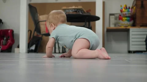 Infant tries to crawl on the grey floor Stock Footage 341631868