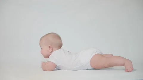An infant on a white background begins to crawl on its stomach Stock Footage 237241901