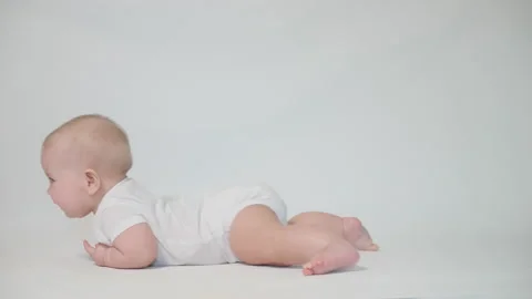 An infant on a white background begins to crawl on its stomach. the first acq Stock Footage 237242403