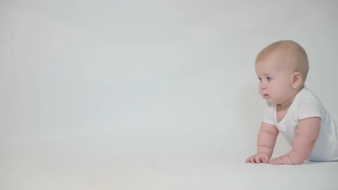 Infant on a white background exploring the surroundings. shot in the studio Stock Footage 237241021