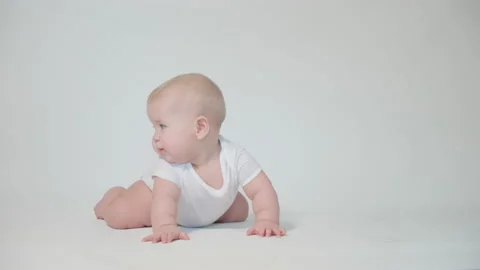 Infant on white background first attempts to crawl on his knees Video stock 237245104