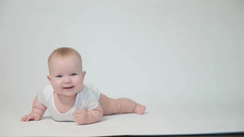 Infant on white background learning to crawl on his stomach Video stock 237244570