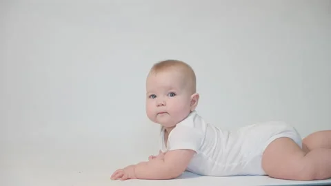 Infant on white background lying on his belly looking at the camera Stock Footage 237240530