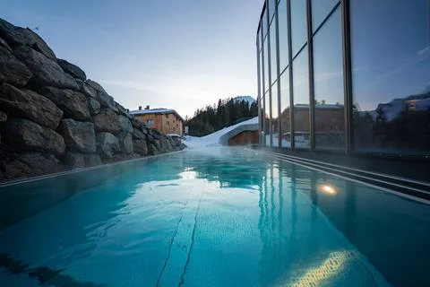 Infinity edge pool by glass walled spa at Oberlech, Austria at dusk Stock Photos