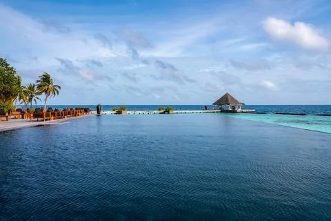 Infinity pool and thatched pavilion at Maldives resort by Indian Ocean Stock Photos