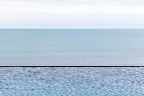 Infinity pool blending seamlessly with tranquil sea and sky, conveying peace  Stock Photos