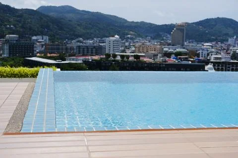 Infinity pool with clear blue water overlooking a cityscape and mountains in the Stock Photos
