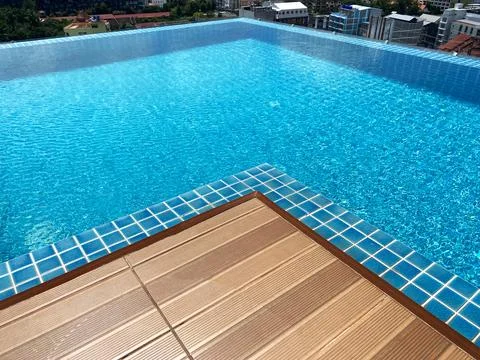 Infinity pool with clear blue water and tiled edges overlooking a cityscape Stock Photos