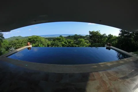 Infinity pool of a luxury house with view of the rainforest and beach, fisheye Stock Photos