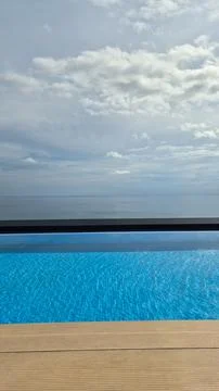 Infinity pool with ocean view under cloudy sky. Luxury travel, resort vacation a Fotos Stock
