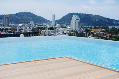 Infinity pool overlooking a vibrant cityscape with mountains in the background Stock Photos