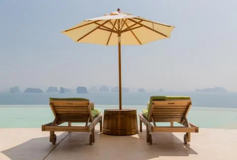 Infinity pool with parasol and sun beds at seaside Stock Photos