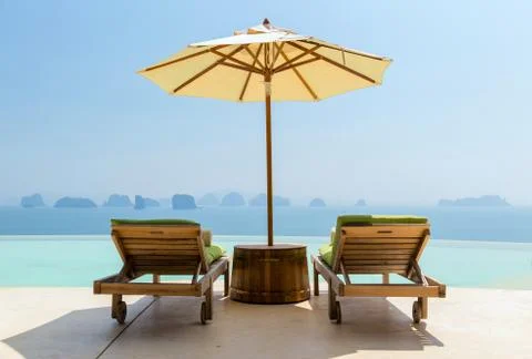 Infinity pool with parasol and sun beds at seaside Stock Photos