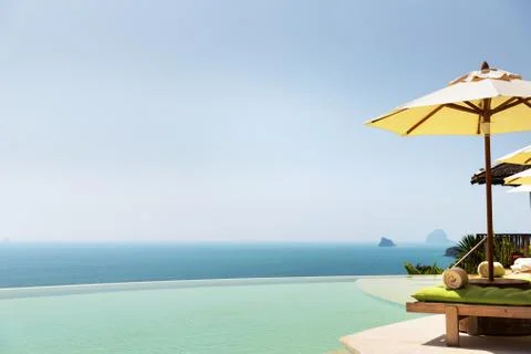 Infinity pool with parasol and sun beds at ocean Stock Photos