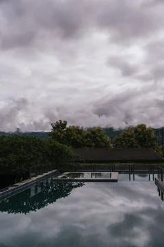 Infinity pool reflecting a dramatic sky with mountains in Pai, Thailand Stock Photos