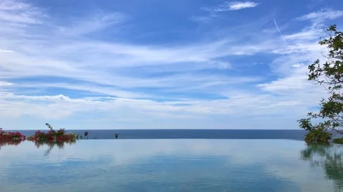 Infinity pool, sea, trees, flowers, horizon and blue sky. Clouds on a sunny day. Stock Footage 99036366