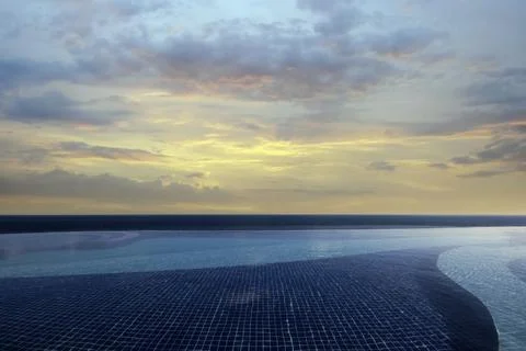 Infinity pool at sunset with a serene ocean view and colorful sky Stock Photos