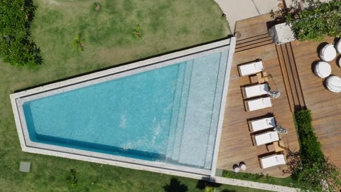 Infinity pool top down aerial with sun loungers and wooden deck luxury resort Stock Footage 334422774