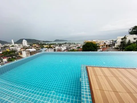Infinity pool with turquoise tiles overlooking a coastal cityscape and ocean Stock Photos