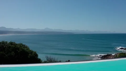 Infinity pool view crytsal clear water revealing ocean and mountains aerial Video stock 329104239