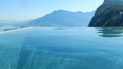 Infinity Swimming Pool with Mountain and Lake View in a Sunny Summer Day 動画素材 202523941