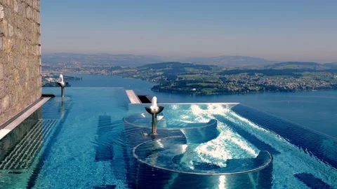 Infinity Swimming Pool with Mountain and Lake View in a Sunny Summer Day Stockbeeldmateriaal 203484292