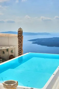 Infinity swimming pool overlooking the Aegean Sea and volcanic islands with s Stock Photos