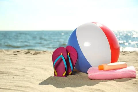 Inflatable ball and beach objects on sand near sea, space for text Stock-Fotos