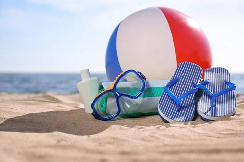 Inflatable ball and beach objects on sand near sea, space for text Stock-Fotos