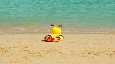 An inflatable beach toy lies alone on a sandy beach by the sea. 스톡 동영상 330061764