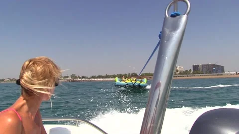 Inflatable couch raft pulled by sea motor boat on sunny day Stock Footage 143637249