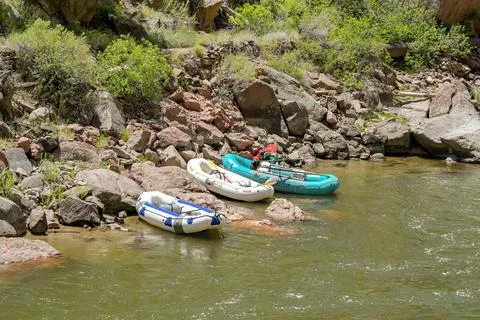 Inflatable dinghies pulled onto the shore of a river Stock Photos
