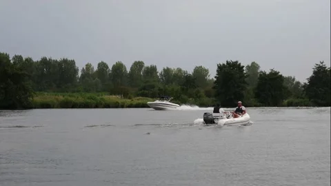 A inflatable dinghy is going upstream, a  day cruiser is salling downstream Stock Footage 141344160