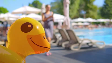 Inflatable duck floating by a sunny poolside in 4k slow motion 60fps Vídeos de archivo 283828519