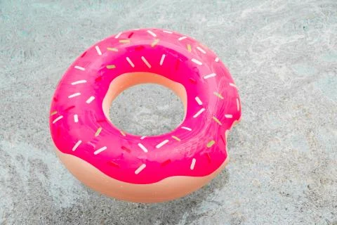 Inflatable float rubber ring in the form of a pink donut in the water of the Stock Photos